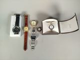 trois montres et un coffret à montres posés sur une table