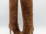 un gros plan sur une paire de bottes en daim marron sur fond blanc