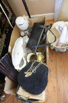 une boîte remplie de sacs à main et d'autres objets, posée par terre