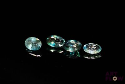 three blue topazte gems sitting on a black surface