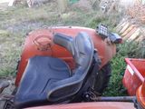 un tracteur rouge avec un siège noir, posé dans l'herbe