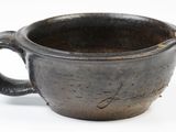 a black cup with a handle on a white surface