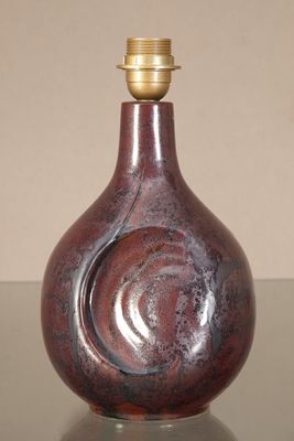 a red vase sitting on a table with a light on top of it