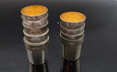 two silver cups with coins on them sitting on a black surface