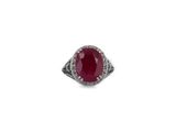 a close up of a ring with a red stone surrounded by diamonds