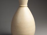 a white vase sitting on top of a table next to a gray wall