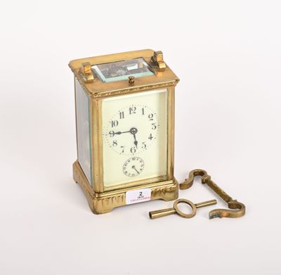une petite horloge dorée avec une clé, posée sur une surface blanche