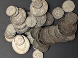 a pile of old silver coins on a black surface