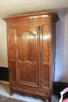 a wooden armoire in the corner of a room