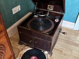 un vieux tourne-disque posé par terre à côté d'une commode
