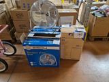 de nombreux cartons et un ventilateur posé par terre dans une pièce