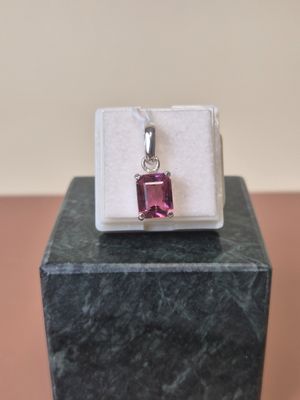a close up of a pink stone pendant sitting on a marble block