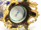 a gold and blue vase sitting on a white surface