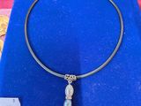 un collier avec une perle en verre et un fermoir en argent, présenté dans une boîte bleue