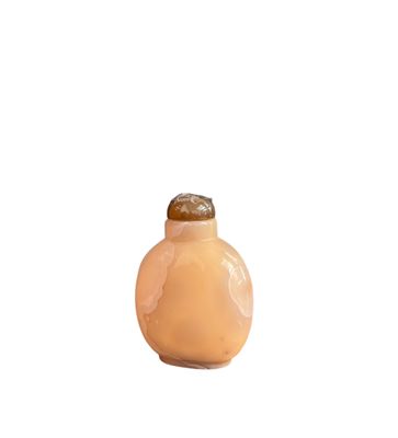 une petite bouteille en verre avec un bouchon marron posée sur une surface blanche