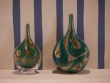 two green vases sitting on a table with blue and white stripes