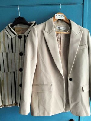 deux vestes accrochées à une porte bleue, à côté d'une paire de chaussures