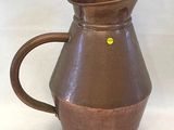 un pichet marron orné d'un point jaune
