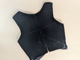 black leather vest on a white surface with a hole in the middle