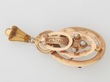 gros plan d'un pendentif en or sur une surface blanche