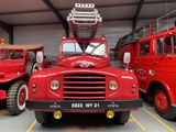 a large red truck parked in a garage with other trucks in the background