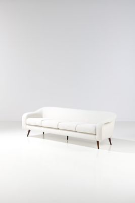 un canapé blanc posé sur un sol blanc, à côté d'un mur blanc