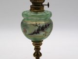 une lampe ancienne en laiton et en verre vert, ornée d'un oiseau