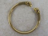 a close up of a gold bracelet with two skulls on it