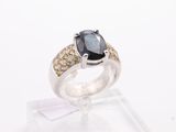 a black diamond and yellow diamond ring on a clear stand