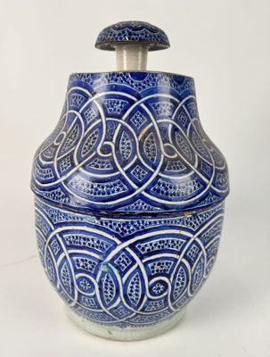 a blue and white vase with a lid on a white surface