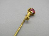 an image of a gold stick with a pink stone on it