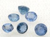 un groupe de cinq saphirs bleus posés sur une surface blanche