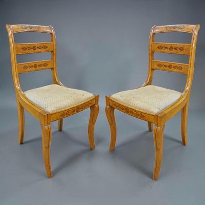 deux chaises en bois avec des assises rembourrées beiges sur fond gris