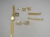 a gold bracelet, a watch, and other jewelry on a table