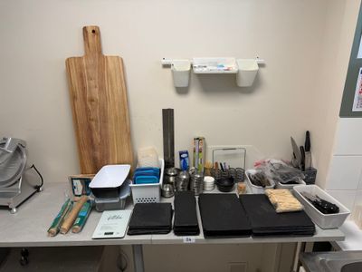 un bureau sur lequel se trouvent un ordinateur portable, une planche à découper et d'autres ustensiles de cuisine