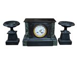 une horloge noire et deux bougies sur fond blanc