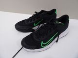 des chaussures de course Nike noires et vertes posées sur une surface blanche
