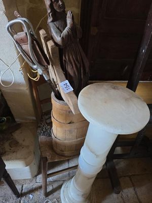 une statue représentant une femme assise sur un tabouret à côté d'un tonneau en bois