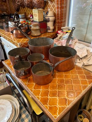 des casseroles et des poêles posées sur une table dans une cuisine dotée d'une fenêtre