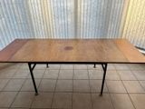 a wooden table with black legs on a tiled floor
