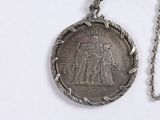 a silver coin with a chain around it on a white surface