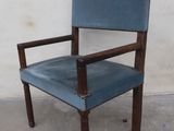 a blue leather chair with a wooden frame on a concrete floor