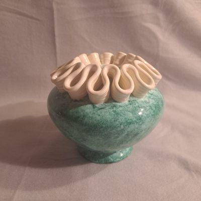 un vase vert contenant des fleurs blanches, sur fond blanc