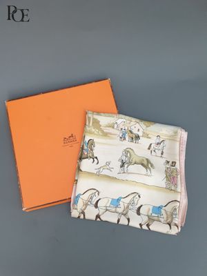 une boîte orange ornée d'un motif représentant un cheval et une calèche, à côté d'une boîte orange ornée d'un motif représentant un cheval et une calèche, à côté d'une boîte orange avec un cheval