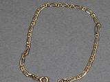 gros plan d'un bracelet en chaîne en or sur une surface grise