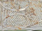 a white chair with a rusted seat on a green background