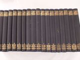 six livres noirs aux tranches dorées sont alignés sur une surface blanche