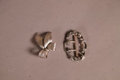 deux broches en argent posées sur une table, ornées d'un papillon