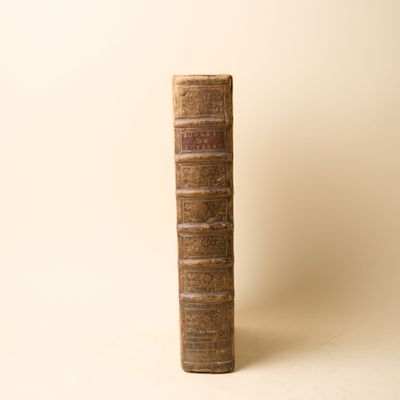 un vieux livre posé sur une table à côté d'un mur blanc