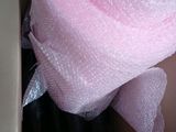 a pink rose wrapped in bubble wrap in a cardboard box